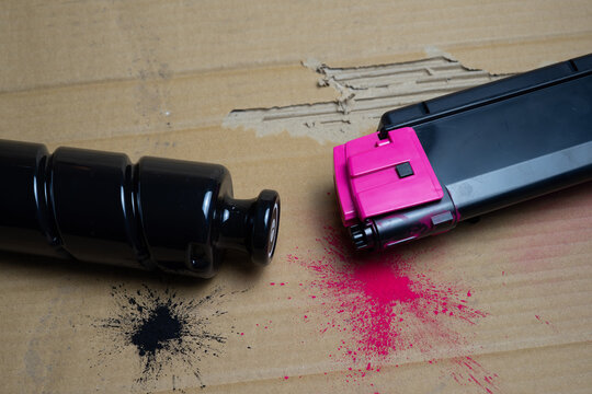 Black and magenta toner cartridges on recycled cardboard with copy space, printer recycling concept