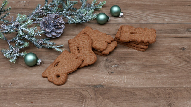 Traditional spiced speculoos cookies on a rustic wooden table with Christmas decorations and plenty of space for text.