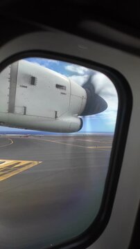 Passenger's point of view from an airplane window watching a propeller engine as the aircraft takes off from the runway in Gran Canaria, Spain, showing the ocean in the distance