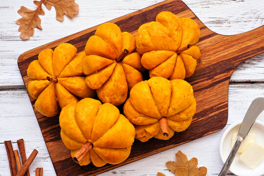 Fall pumpkin shaped buns. Top view table scene over a white wood background.