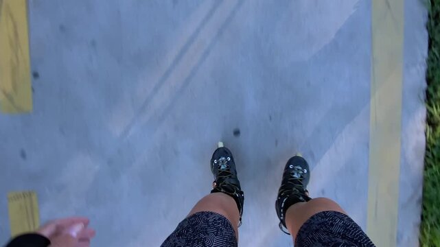Woman rollerblading in top-down view along a marked paved lane, showing inline skates and body shadow in motion, suited for fitness tracking, urban exercise, active transport and recreation content