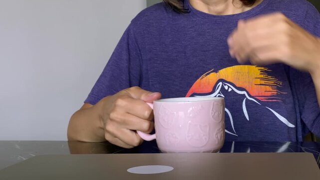 Woman opening laptop, front view at a table with coffee nearby, showing the start of a work session for remote work, online tasks, productivity, home office routines and digital business use