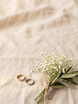 Copertina libro amore con fedi nuziali e bouquet di fiori bianchi su uno sfondo di lino beige