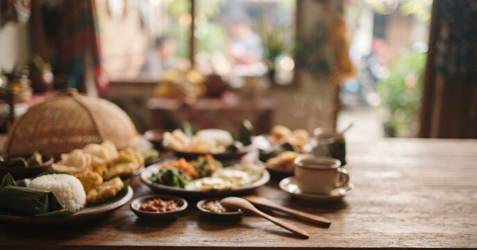 Cozy Indonesian breakfast scene with rice, eggs, snacks, tea, coffee, and traditional serving elements intentionally softened into morning bokeh for authentic culinary lifestyle backgrounds