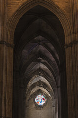 Obraz premium Stained glass rose window glowing above the crucifix in Seville Cathedral's Gothic nave