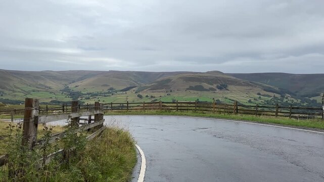 Driving down steep winding road from Mam Tor towards Edale in Peak District, car POV, point of view, driving plate.
