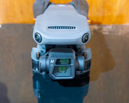 Front view of grey foldable quadcopter drone with dual camera system Hasselblad lens and obstacle avoidance sensors on reflective surface