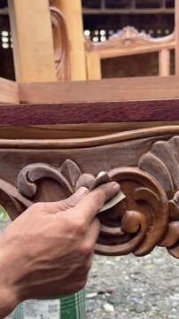 Sanding carved wooden furniture with sandpaper close up