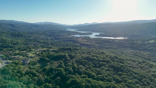 Aerial view flying over lush forest towards As Conchas reservoir