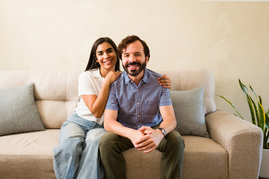 Cheerful couple relaxing on sofa at home, smiling while enjoying quality time together in a relationship