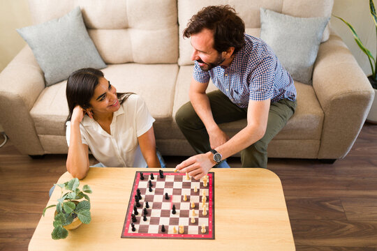 Happy couple enjoying a date night playing chess and spending quality time together at home