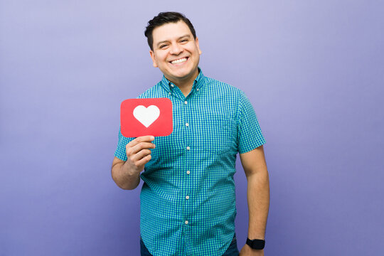 Happy man holding social media heart like icon, representing online approval, digital marketing, and influencer content