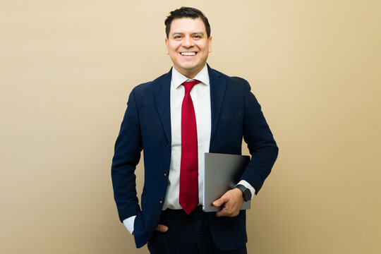Businessman holding a laptop and smiling, representing corporate success, career, and achievement