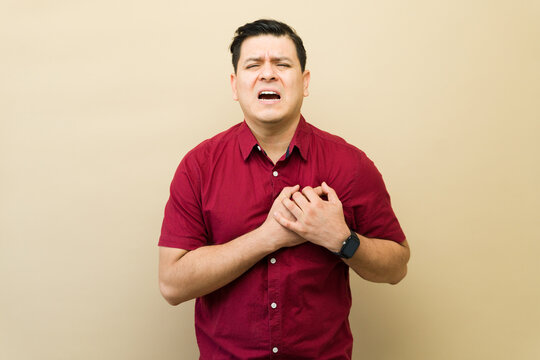 Man suffering heart attack clutching chest feeling strong pain, experiencing cardiovascular emergency or symptom