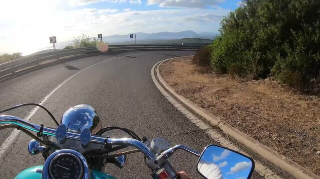 POV ride on a custom turquoise motorcycle descending a winding rural road, with natural engine and exhaust sounds creating an immersive first person motorcycle travel experience.