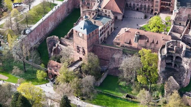heidelberg castle clock tower moat garden courtyard rooftops red sandstone ruins fortress walls baden wurttemberg germany aerial orbit drone footage elevated view historic heritage site landmark