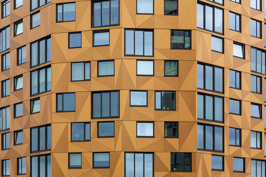 Modern building facade featuring geometric copper panels and windows