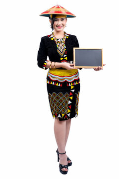 Beautiful Dayak young women in Lun Bawang traditional clothing holding a blackboard on white background