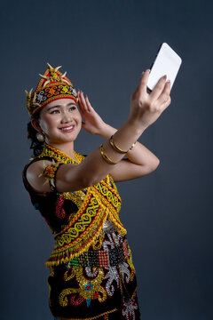 Beautiful young woman in Kenyah Orang Ulu traditional cloth holding a smartphone