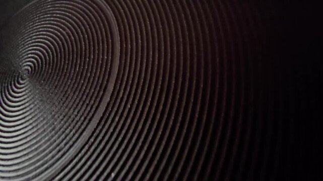 Abstract dark metallic background with concentric circular pattern and warm lighting macro close up.