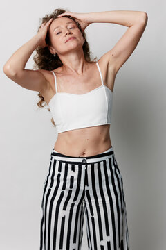 Authentic beauty of a middle aged woman with natural skin without retouching. She poses gracefully against a light background, showcasing confidence and self acceptance in lifestyle.