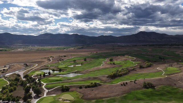Aerial of golf course in Lakewood Colorado backed by front range foothills with dark clouds showing manicured fairways