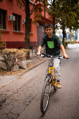 Fototapeta premium Young boy riding bicycle on urban street