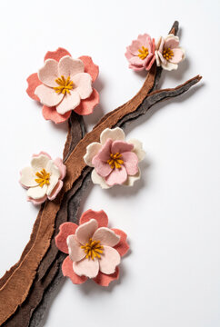 Cherry blossoms made of felt on a branch against a white background  