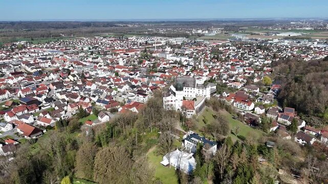 illertissen bavarian town aerial view red tile rooftops vohlin castle hillside treeline farmland industrial park distant skyline drone footage rural landscape swabia germany travel destination