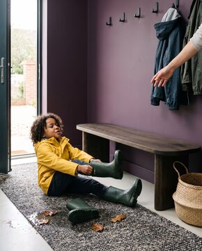 Wet wellington boots and leaves in the hallway in autumn