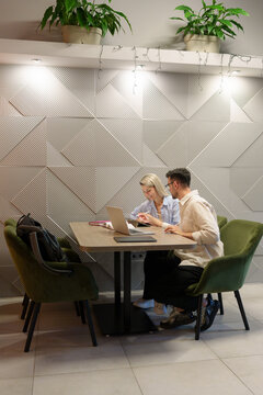 Two people collaborating together on a laptop in a modern workspace