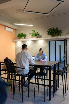 Modern coworking space with two colleagues working at a high table.