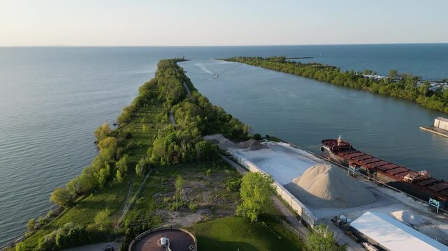 Moving back aerial of the Welland Canal and Sunset Beach in St. Catharines, Ontario, Canada, with a large cargo ship docked. St. Lawrence Seaway connecting Lake Ontario to Lake Erie. May, 2023.