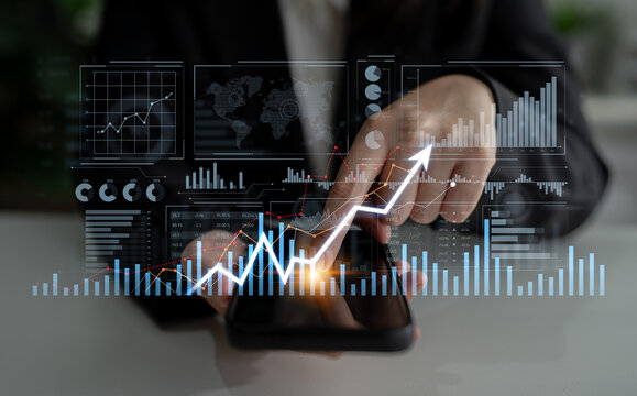 A professional businessperson interacts with a smartphone displaying financial growth trends. The image captures dynamic data charts and graphs in a modern workspace. Scalp