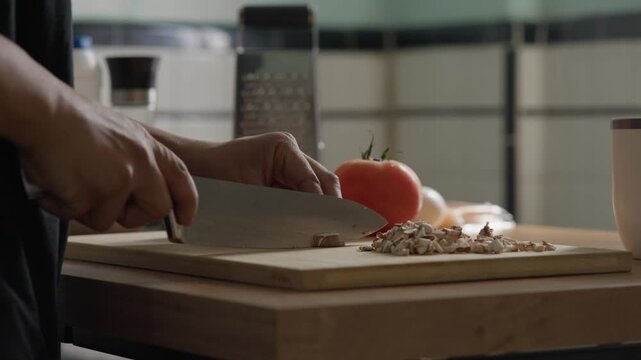man cutting mushrooms on a cutting board in a sun window lit kitchen