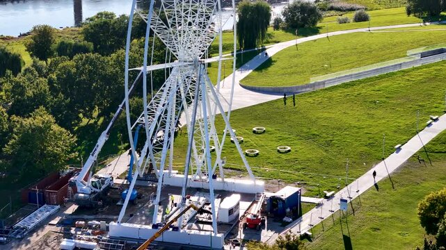 Aerial drone footage of a Ferris wheel under construction on Nemunas Island in Kaunas, Lithuania, showing a new observation attraction rising in the city center. 4K video 