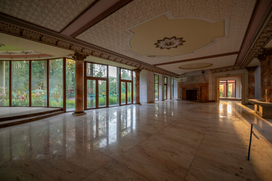 Abandoned luxury mansion interior with marble hall, ornate fireplace, swimming pool and glass facade