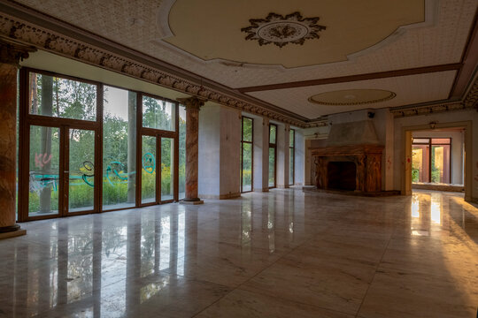 Abandoned luxury mansion interior with marble hall, ornate fireplace, swimming pool and glass facade