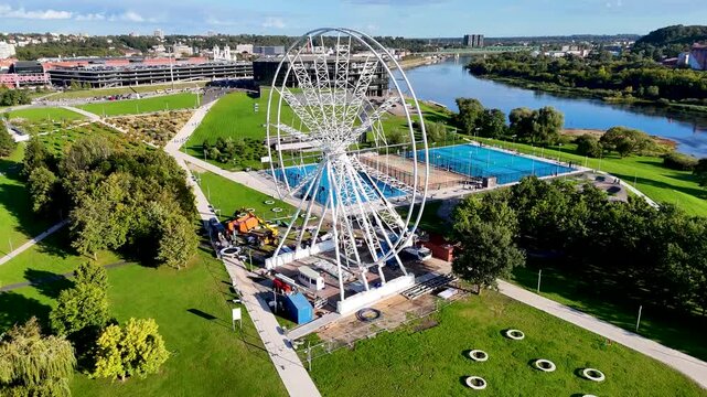 Aerial drone footage of a Ferris wheel under construction on Nemunas Island in Kaunas, Lithuania, showing a new observation attraction rising in the city center. 4K video 