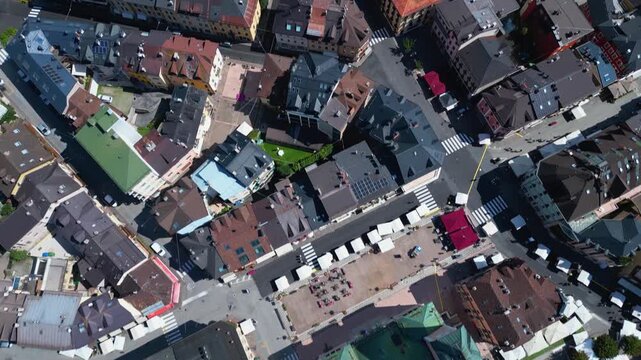 Top-down aerial tilt up revealing streets, rooftops, and sports facilities in Asiago town center, Italy