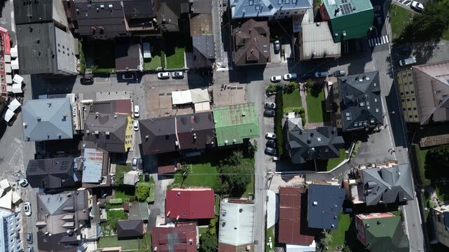 Top-down aerial tilt up revealing streets, rooftops, and sports facilities in Asiago town center, Italy