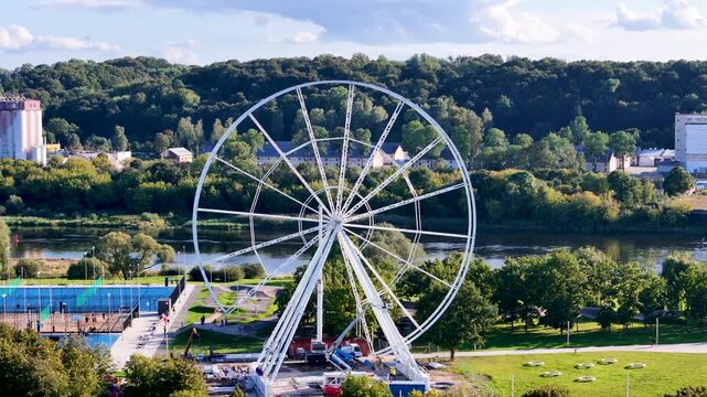 Aerial drone footage of a Ferris wheel under construction on Nemunas Island in Kaunas, Lithuania, showing a new observation attraction rising in the city center. 4K video 
