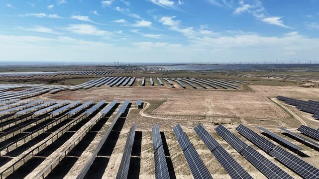 Rows of solar panels in a vast open field under blue sky