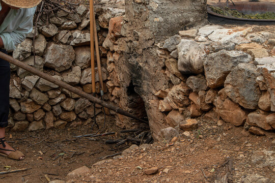Overview of a traditional outdoor stone oven with a copper kettle and woven baskets in Spanish viticulture