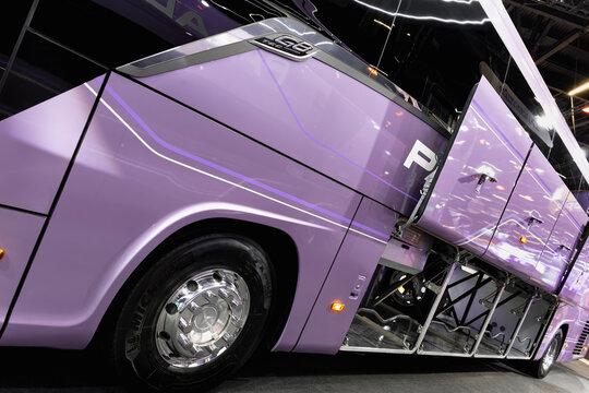 Side view of a Marcopolo G8 TEC bus, featuring a chrome front wheel and open side compartments on display