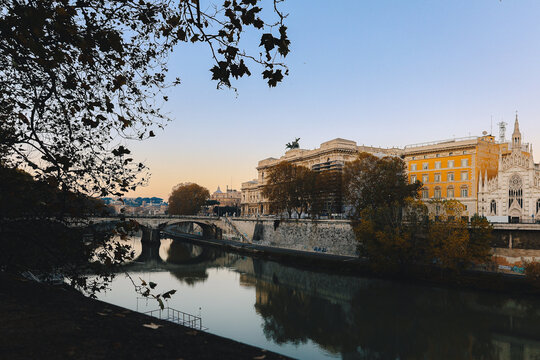 Classical architecture and arched bridge over river with soft evening tones and reflections creating timeless urban landscape in Italy, Rome, Italy.