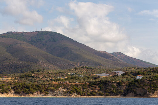 The coastline of Thassos Island. The marine landscape in Greece. Rocks, sea, trees, sky.