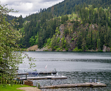 Wooden Dock on a Calm Lake on Evergreen Forest and Rocky Cliff Background