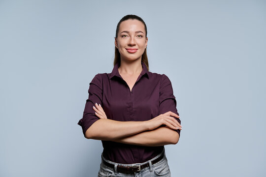 Young woman with arms crossed smiling confidently on light background