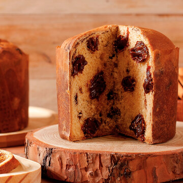 Homemade Christmas panettone with creamy chocolate on a rustic wooden table set for a Christmas celebration.